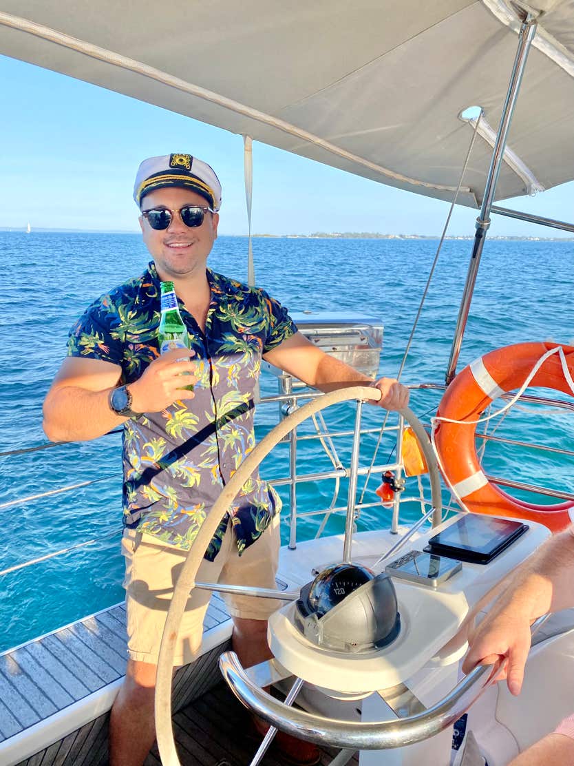 An employee posing for a photo at the whell on a private yacht charter offered as an employee incentive on Moreton Bay Brisbane.