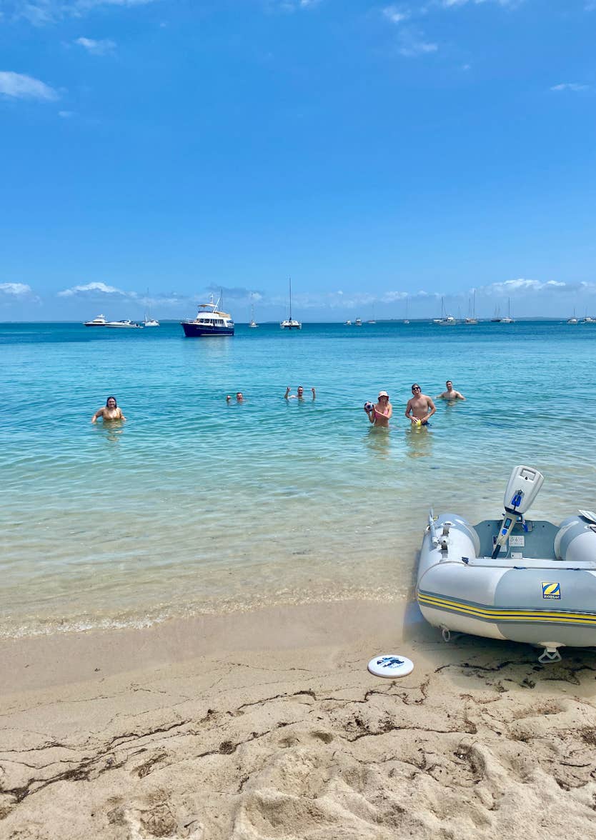 Friends swimming from the beach while on a private yacht charter aboard sailing yacht Curlew Escape in Moreton Bay, Brisbane.