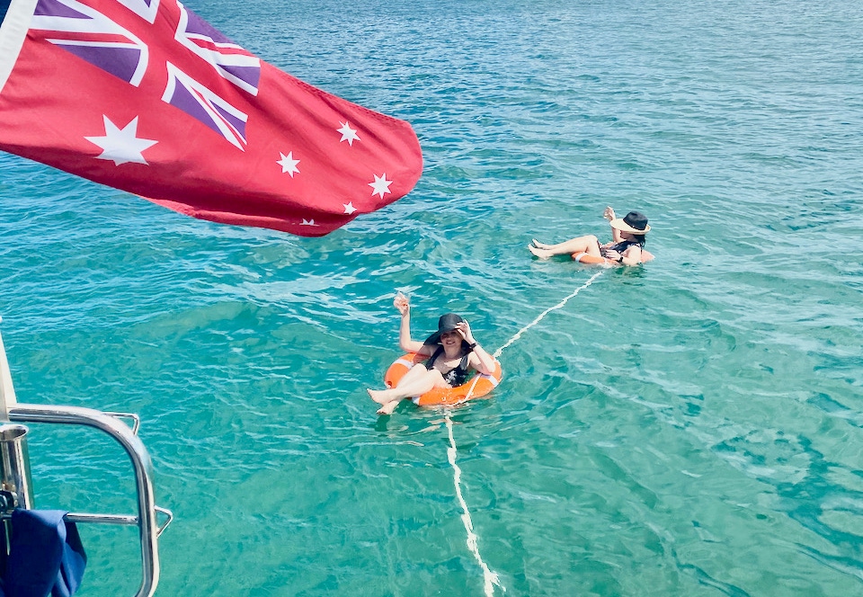 Friends swimming from the yacht while on a private yacht charter aboard sailing yacht Curlew Escape in Moreton Bay, Brisbane.