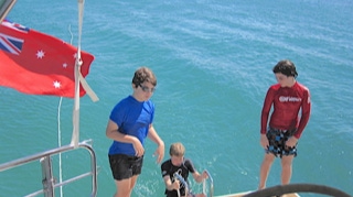 Boys boarding the yacht after swimming on  Sailing Yacht Curlew Escape, available for private yacht charters on Moreton Bay, Brisbane.