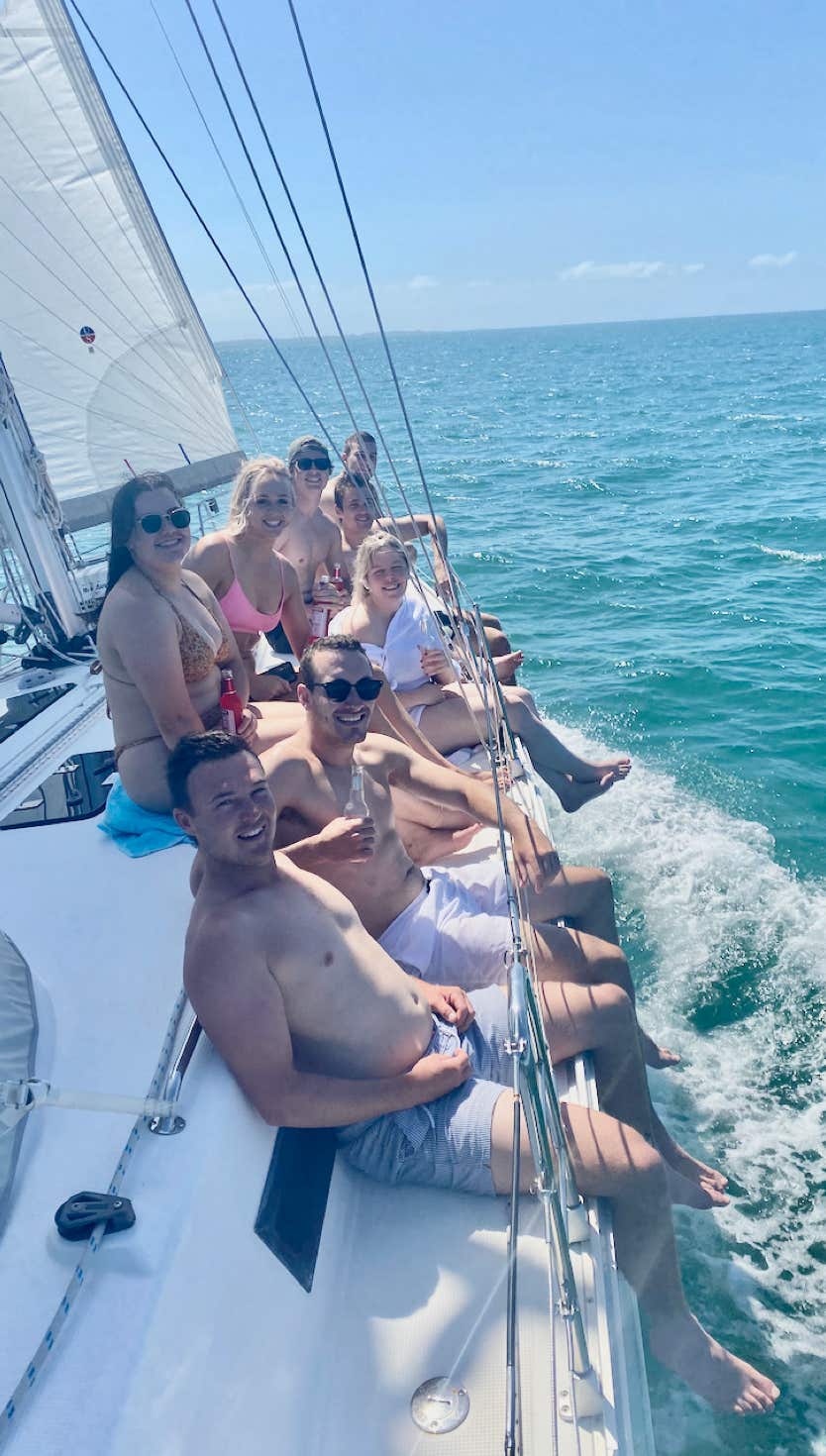 Friends on the rail aboard sailing yacht Curlew Escape on a private yacht charter in Moreton Bay, Brisbane.